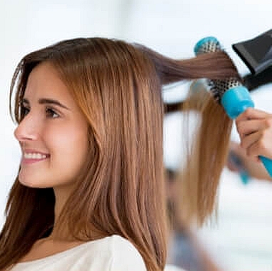 Woman getting her long hair blowed dried and styled